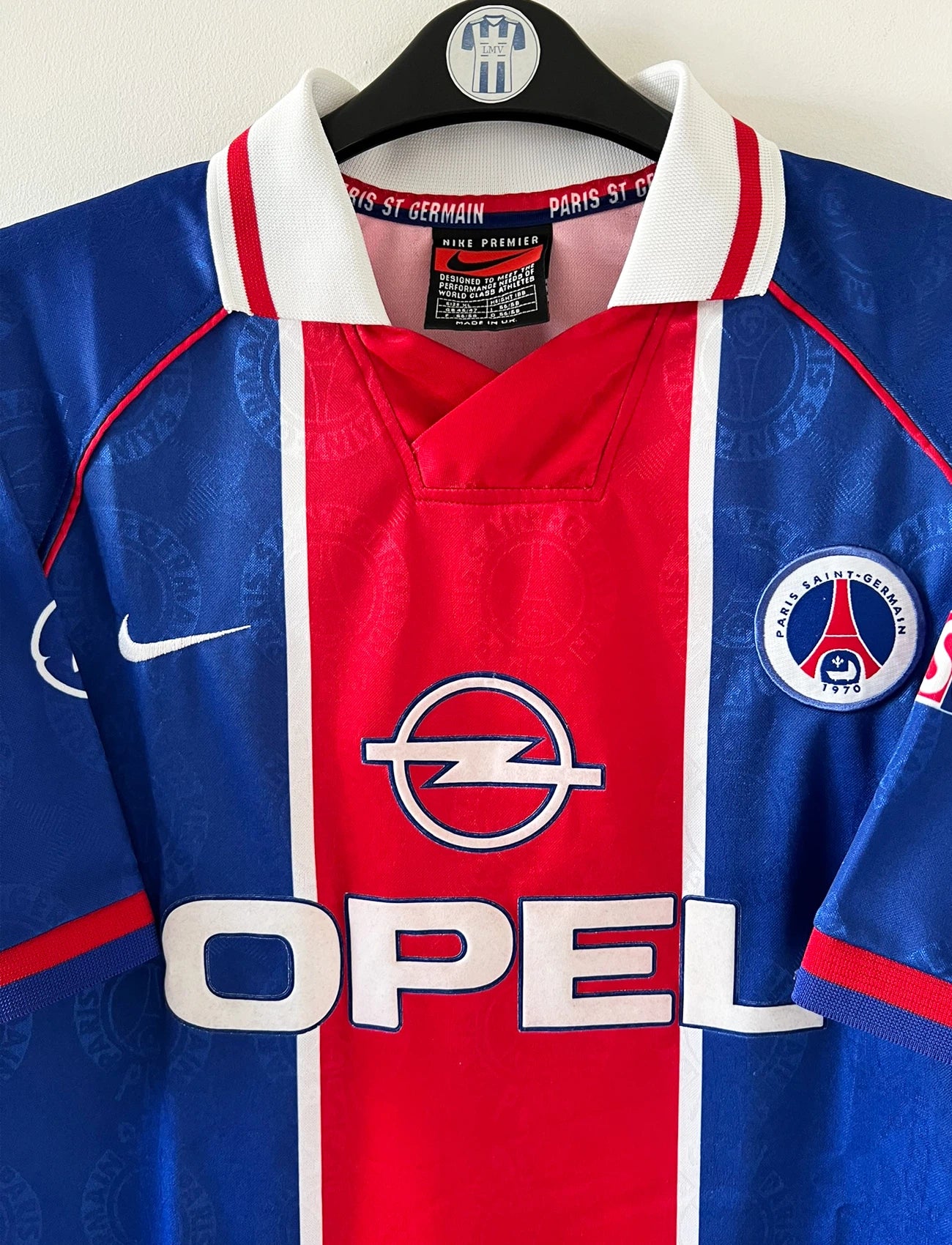 Maillot de foot vintage domicile rouge et bleu du PSG de la saison 1996/1997. On peut retrouver la fameuse bande hechter avec l'équipementier Nike et le sponsor Opel. Il s'agit d'un maillot authentique d'époque.