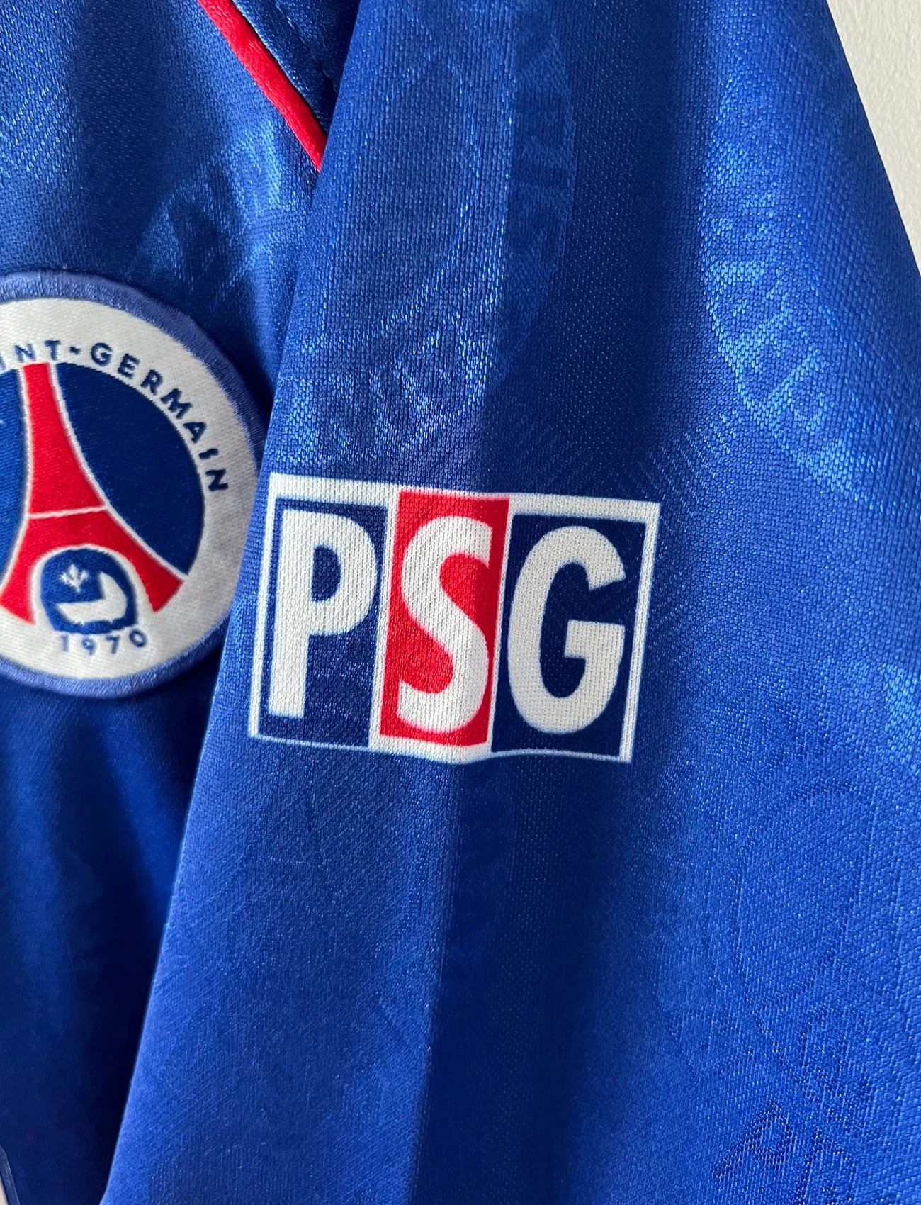 Maillot de foot vintage domicile rouge et bleu du PSG de la saison 1996/1997. On peut retrouver la fameuse bande hechter avec l'équipementier Nike et le sponsor Opel. Il s'agit d'un maillot authentique d'époque.