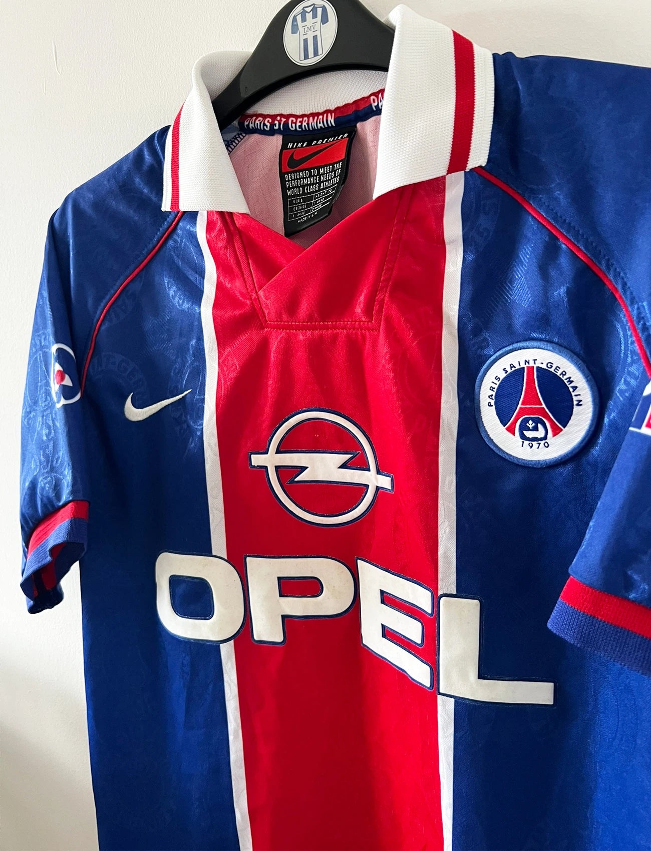 Maillot de foot vintage domicile bleu et rouge du PSG 1996/1997. On peut retrouver l'équipementier Nike et le sponsor OPEL. Il s'agit d'un maillot authentique d'époque.