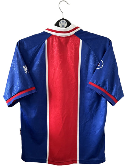 Maillot de foot vintage domicile bleu et rouge du PSG 1996/1997. On peut retrouver l'équipementier Nike et le sponsor OPEL. Il s'agit d'un maillot authentique d'époque.