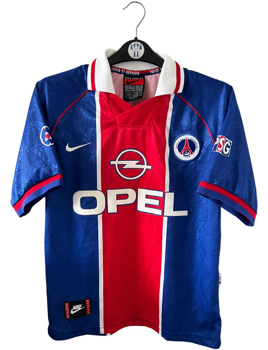 Maillot de foot vintage domicile bleu et rouge du PSG 1996/1997. On peut retrouver l'équipementier Nike et le sponsor OPEL. Il s'agit d'un maillot authentique d'époque.