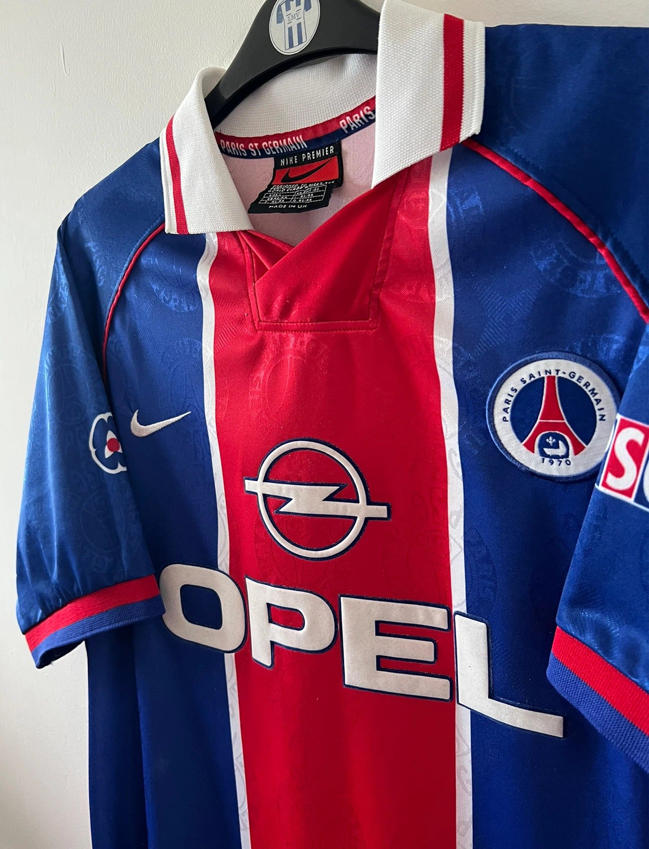 Maillot de foot vintage domicile bleu et rouge du PSG 1996. On peut retrouver l'équipementier Nike et le sponsor Opel. Il s'agit d'un maillot authentique d'époque.