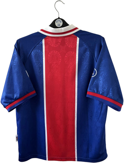 Maillot de foot vintage domicile bleu et rouge du PSG 1996. On peut retrouver l'équipementier Nike et le sponsor Opel. Il s'agit d'un maillot authentique d'époque.