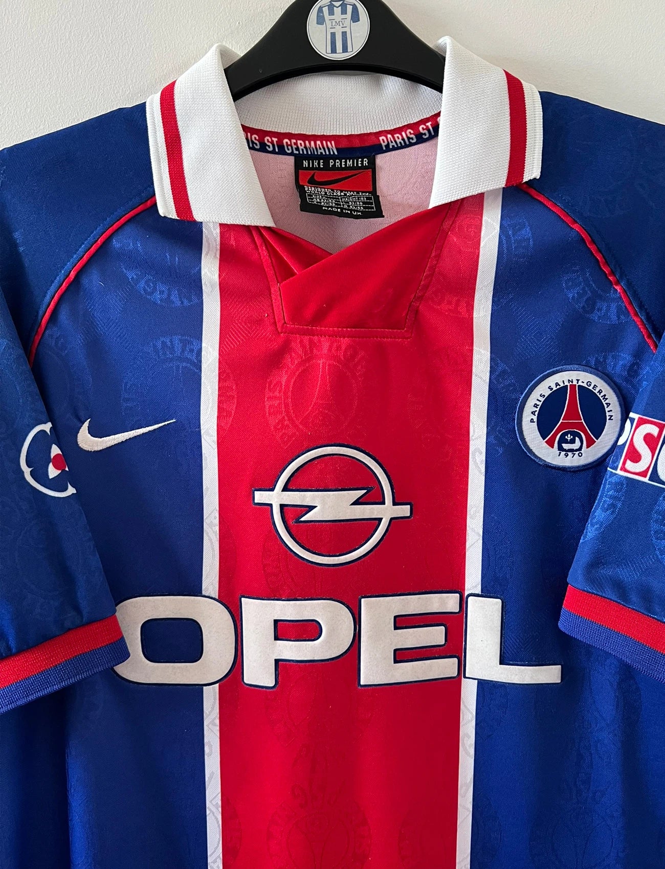 Maillot de foot vintage domicile bleu et rouge du PSG 1996. On peut retrouver l'équipementier Nike et le sponsor Opel. Il s'agit d'un maillot authentique d'époque.