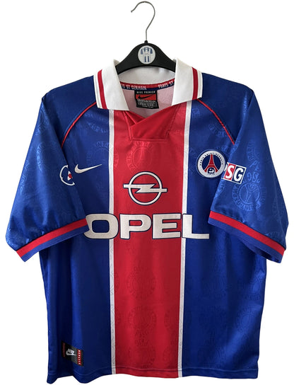 Maillot de foot vintage domicile bleu et rouge du PSG 1996. On peut retrouver l'équipementier Nike et le sponsor Opel. Il s'agit d'un maillot authentique d'époque.