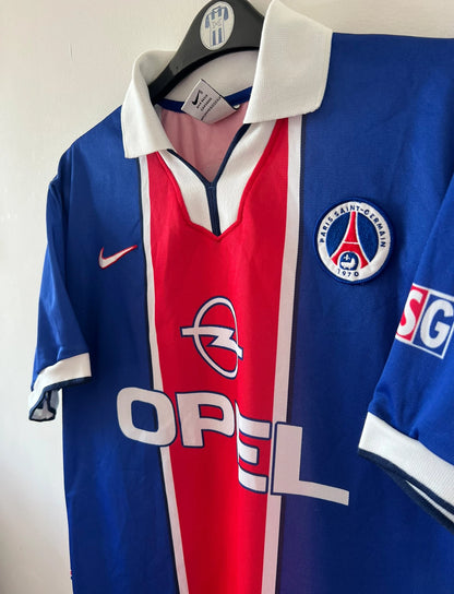 Maillot de foot vintage domicile PSG 1997/1998. On peut retrouver l'équipementier Nike et le sponsor Opel. Le maillot est floqué du numéro 18 Florian Maurice. Il s'agit d'un maillot authentique d'époque.
