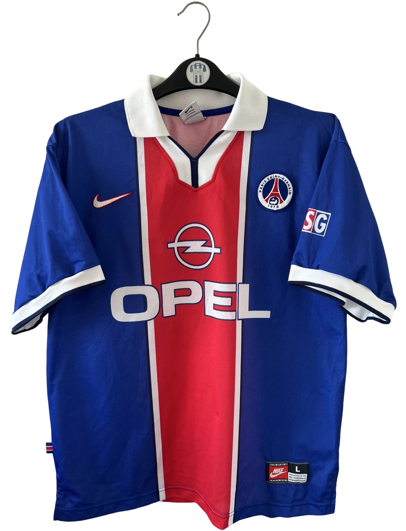 Maillot de foot vintage domicile PSG 1997/1998. On peut retrouver l'équipementier Nike et le sponsor Opel. Le maillot est floqué du numéro 18 Florian Maurice. Il s'agit d'un maillot authentique d'époque.