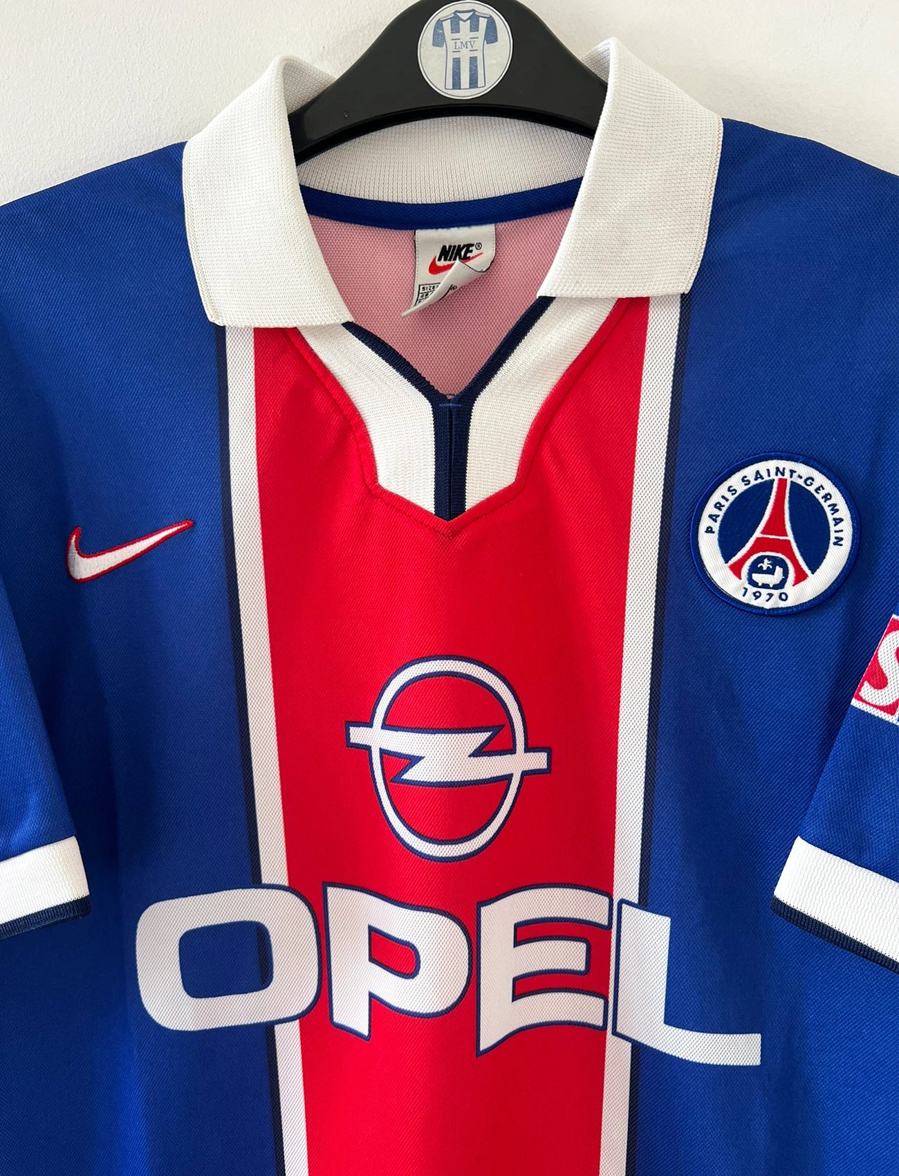 Maillot de foot vintage domicile bleu et rouge du PSG de la saison 1997/1998. On peut retrouver l'équipementier Nike et le sponsor Opel. Il s'agit d'un maillot authentique d'époque.