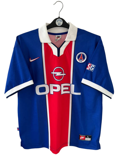 Maillot de foot vintage domicile bleu et rouge du PSG de la saison 1997/1998. On peut retrouver l'équipementier Nike et le sponsor Opel. Il s'agit d'un maillot authentique d'époque.