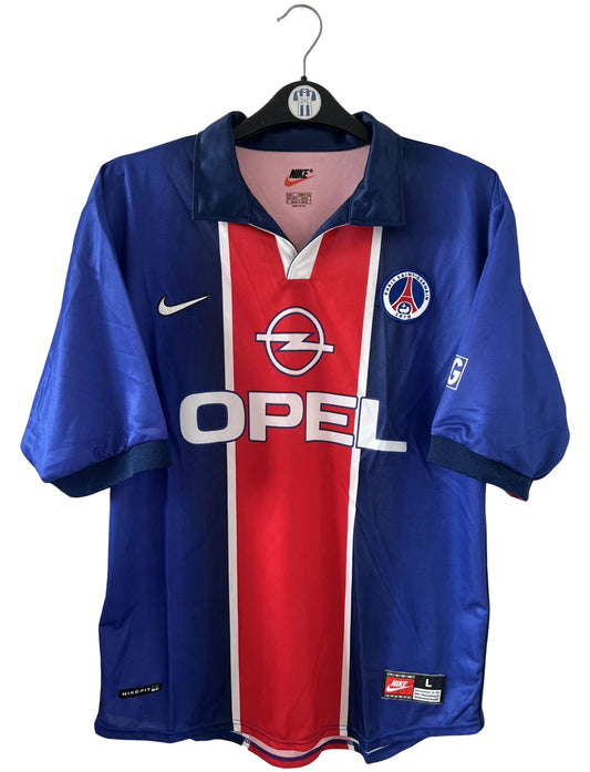 Maillot de foot vintage domicile bleu avec la bande hechter du PSG de la saison 1998/1999. On peut retrouver l'équipementier Nike et le sponsor Opel. Il s'agit d'un maillot authentique d'époque.