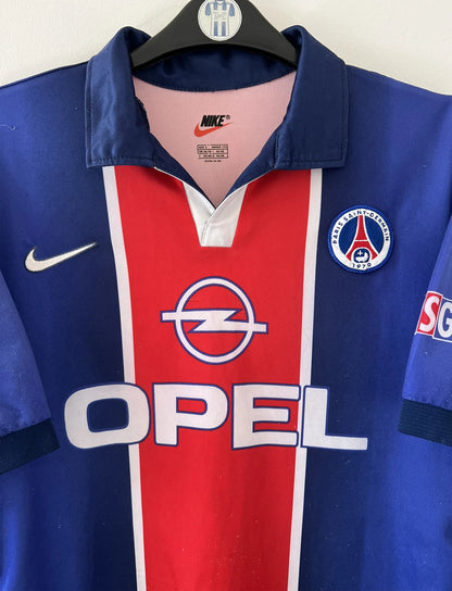 Maillot de foot vintage domicile rouge et bleu du PSG 1998/1999. On peut retrouver l'équipementier Nike et le sponsor OPEL. Il s'agit d'un maillot authentique d'époque.
