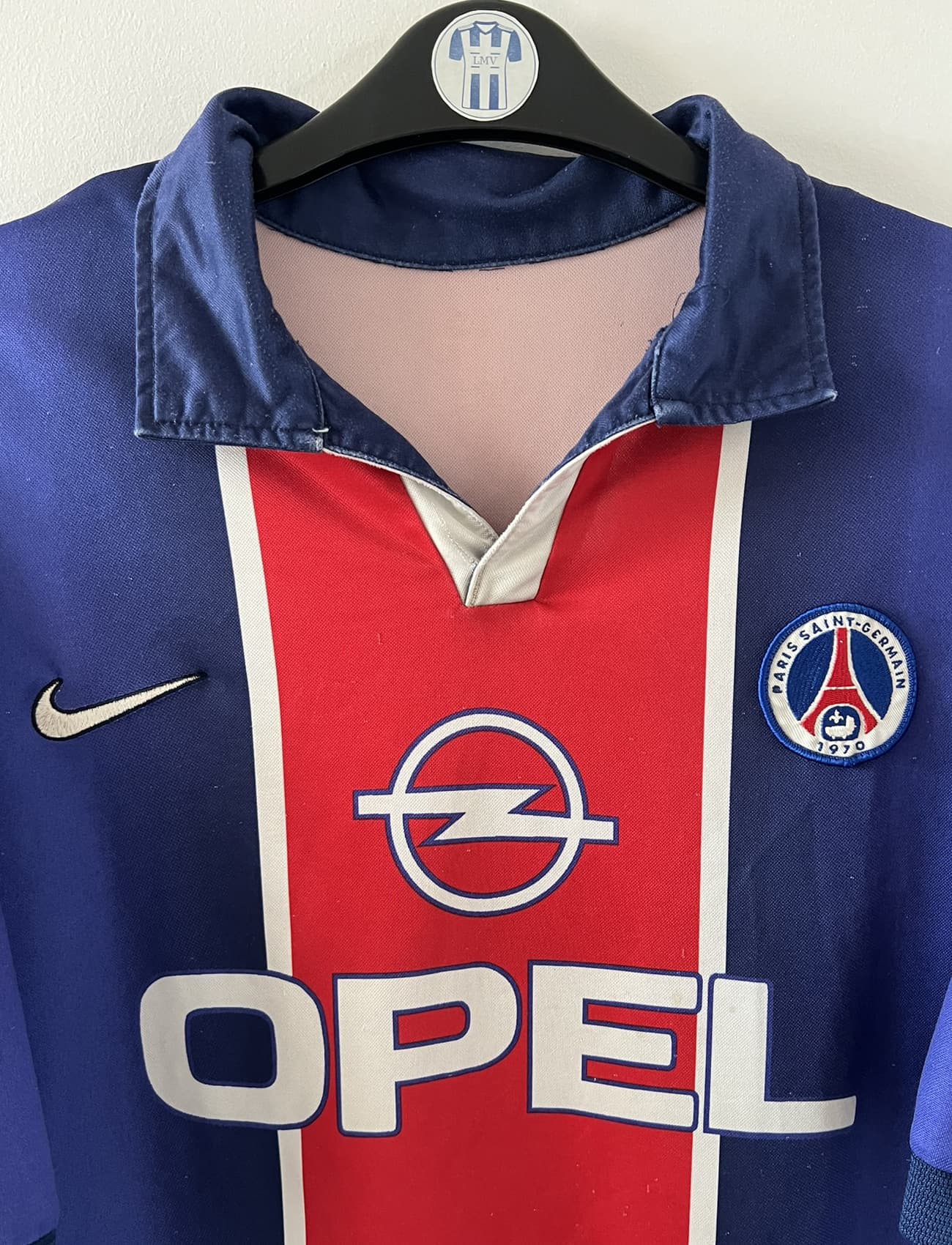 Maillot de foot vintage domicile bleu et rouge du PSG 1998/1999. On peut retrouver l'équipementier Nike et le sponsor Opel. Il s'agit d'un maillot authentique d'époque.
