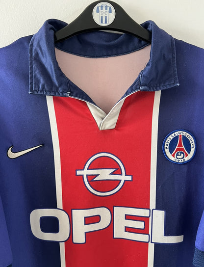 Maillot de foot vintage domicile bleu et rouge du PSG 1998/1999. On peut retrouver l'équipementier Nike et le sponsor Opel. Il s'agit d'un maillot authentique d'époque.