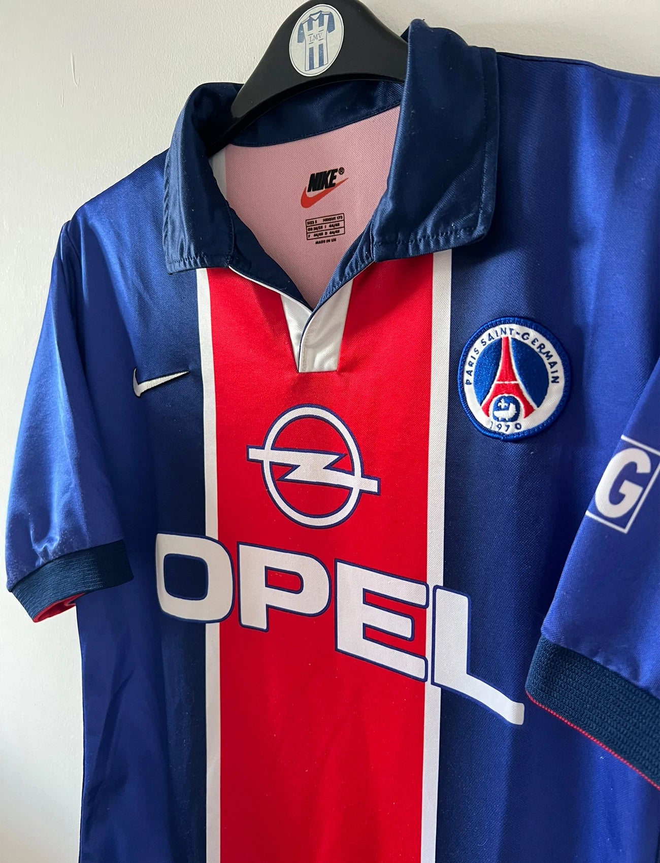 Maillot de foot vintage domicile bleu et rouge du PSG 1998/1999. On peut retrouver l'équipementier Nike et le sponsor Opel. Il s'agit d'un maillot authentique d'époque.