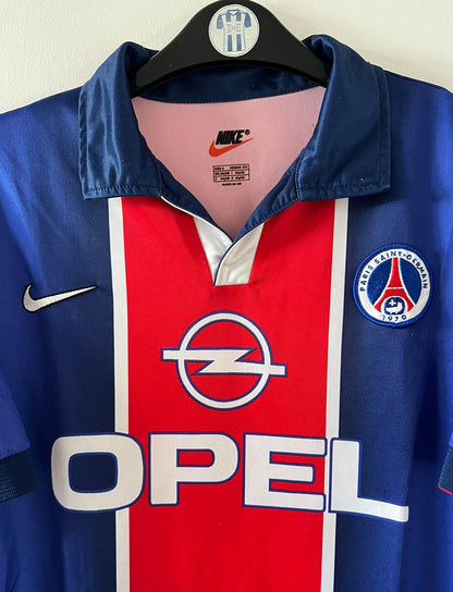 Maillot de foot vintage domicile bleu et rouge du PSG 1998/1999. On peut retrouver l'équipementier Nike et le sponsor Opel. Il s'agit d'un maillot authentique d'époque.