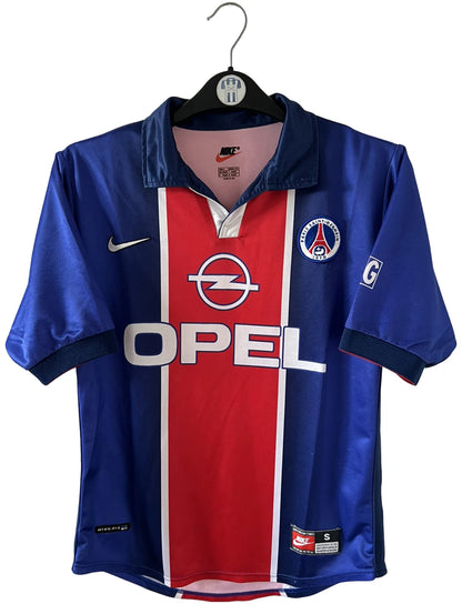 Maillot de foot vintage domicile bleu et rouge du PSG 1998/1999. On peut retrouver l'équipementier Nike et le sponsor Opel. Il s'agit d'un maillot authentique d'époque.