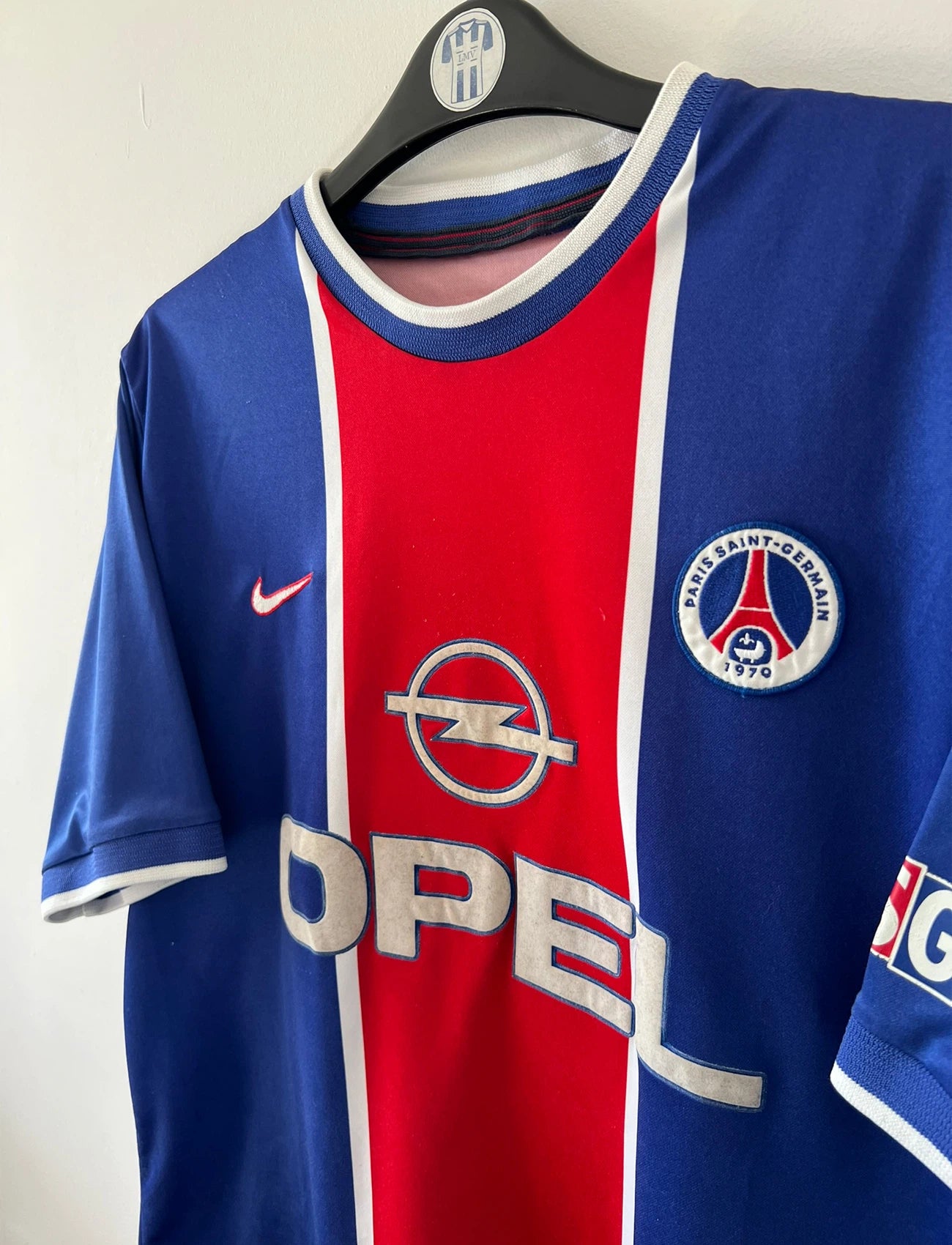 Maillot de foot vintage domicile bleu et rouge du PSG 1999/2000. On peut retrouver l'équipementier Nike et le sponsor Opel. Il s'agit d'un maillot authentique d'époque.