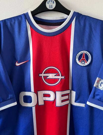 Maillot de foot vintage domicile rouge et bleu du PSG 1999/2000. On peut retrouver l'équipementier Nike et le sponsor OPEL. Il s'agit d'un maillot authentique d'époque.