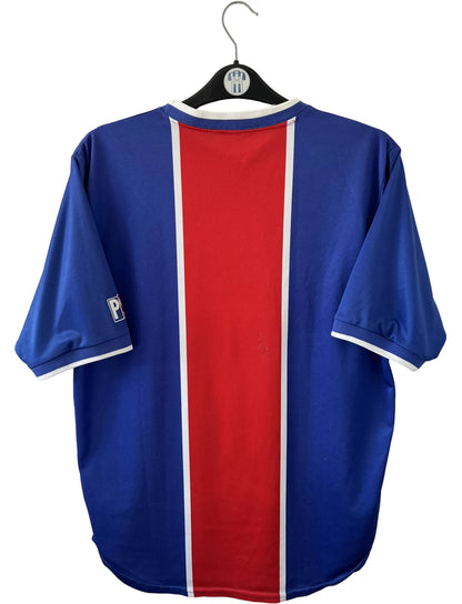 Maillot de foot vintage domicile bleu et rouge du PSG 1999/2000. On peut retrouver l'équipementier Nike et le sponsor Opel. Il s'agit d'un maillot authentique d'époque.