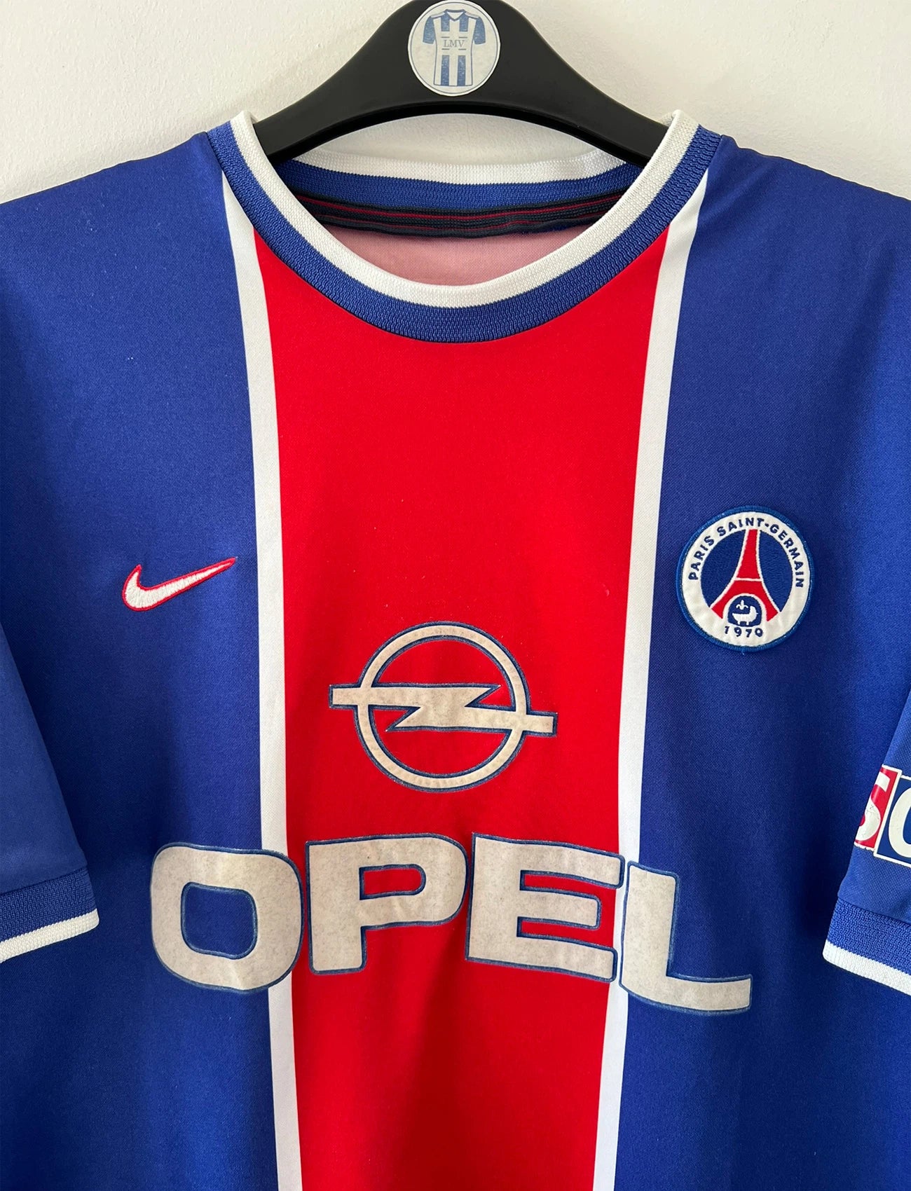 Maillot de foot vintage domicile bleu et rouge du PSG 1999/2000. On peut retrouver l'équipementier Nike et le sponsor Opel. Il s'agit d'un maillot authentique d'époque.