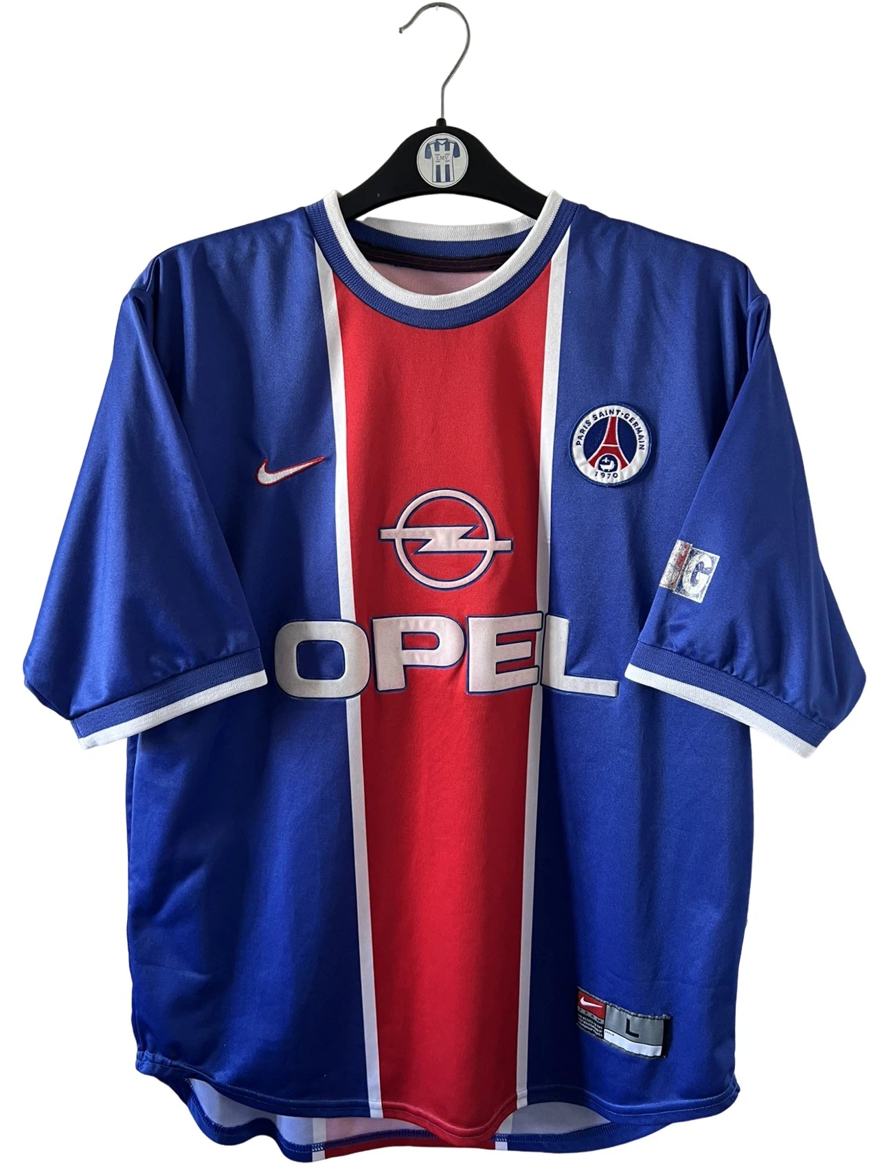 Maillot de foot vintage domicile rouge et bleu du PSG 1999/2000. On peut retrouver l'équipementier Nike et le sponsor OPEL. Il s'agit d'un maillot authentique d'époque.