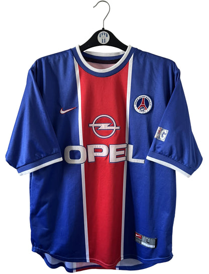 Maillot de foot vintage domicile rouge et bleu du PSG 1999/2000. On peut retrouver l'équipementier Nike et le sponsor OPEL. Il s'agit d'un maillot authentique d'époque.
