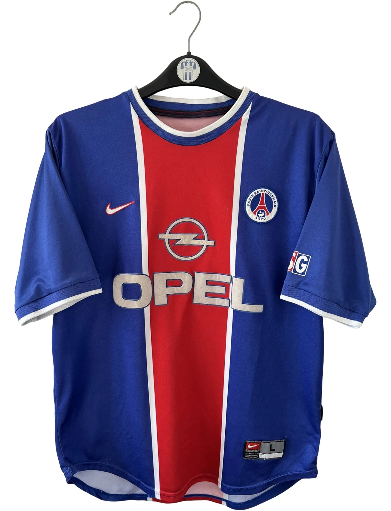 Maillot de foot vintage domicile bleu et rouge du PSG 1999/2000. On peut retrouver l'équipementier Nike et le sponsor Opel. Il s'agit d'un maillot authentique d'époque.
