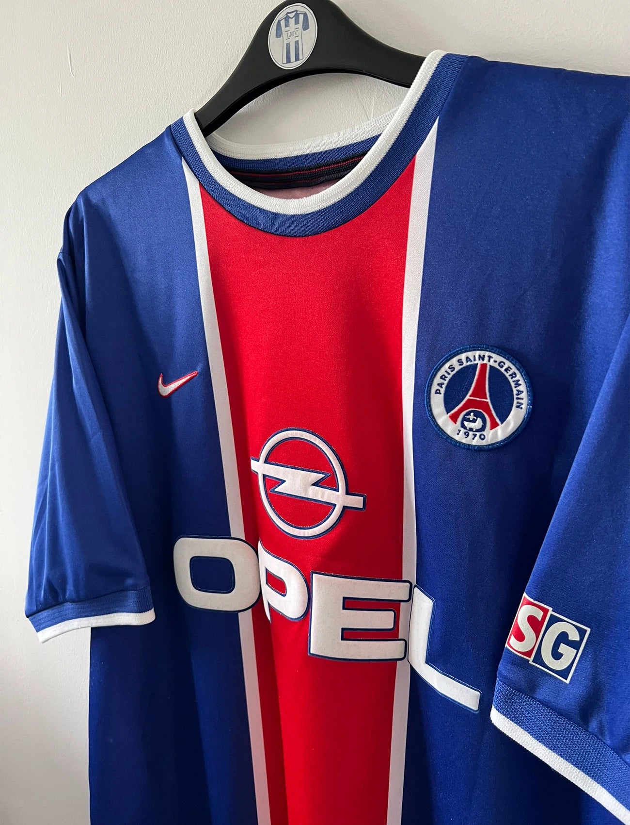 Maillot de foot vintage domicile blanc et rouge du PSG 1999/2000. On peut retrouver l'équipementier Nike et le sponsor Opel. Il s'agit d'un maillot authentique d'époque.