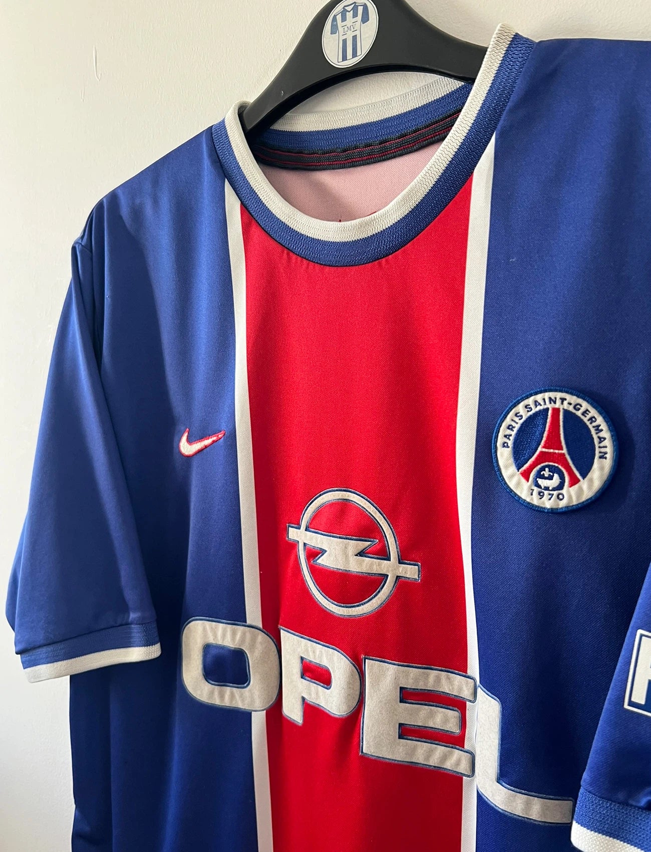 Maillot de foot vintage domicile bleu et rouge du PSG 1999/2000. On peut retrouver l'équipementier Nike et le sponsor Opel. Il s'agit d'un maillot authentique d'époque.