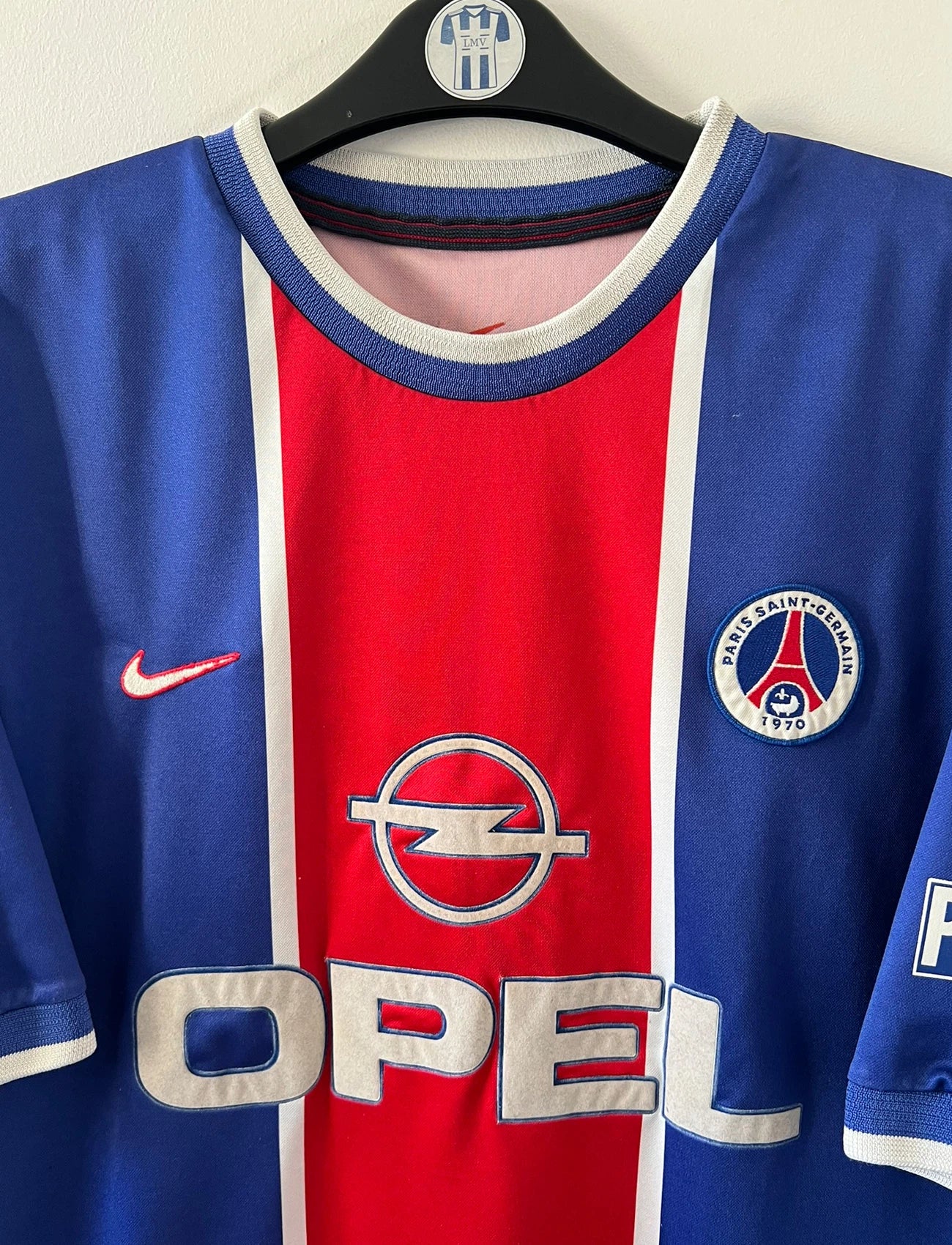 Maillot de foot vintage domicile bleu et rouge du PSG 1999/2000. On peut retrouver l'équipementier Nike et le sponsor Opel. Il s'agit d'un maillot authentique d'époque.