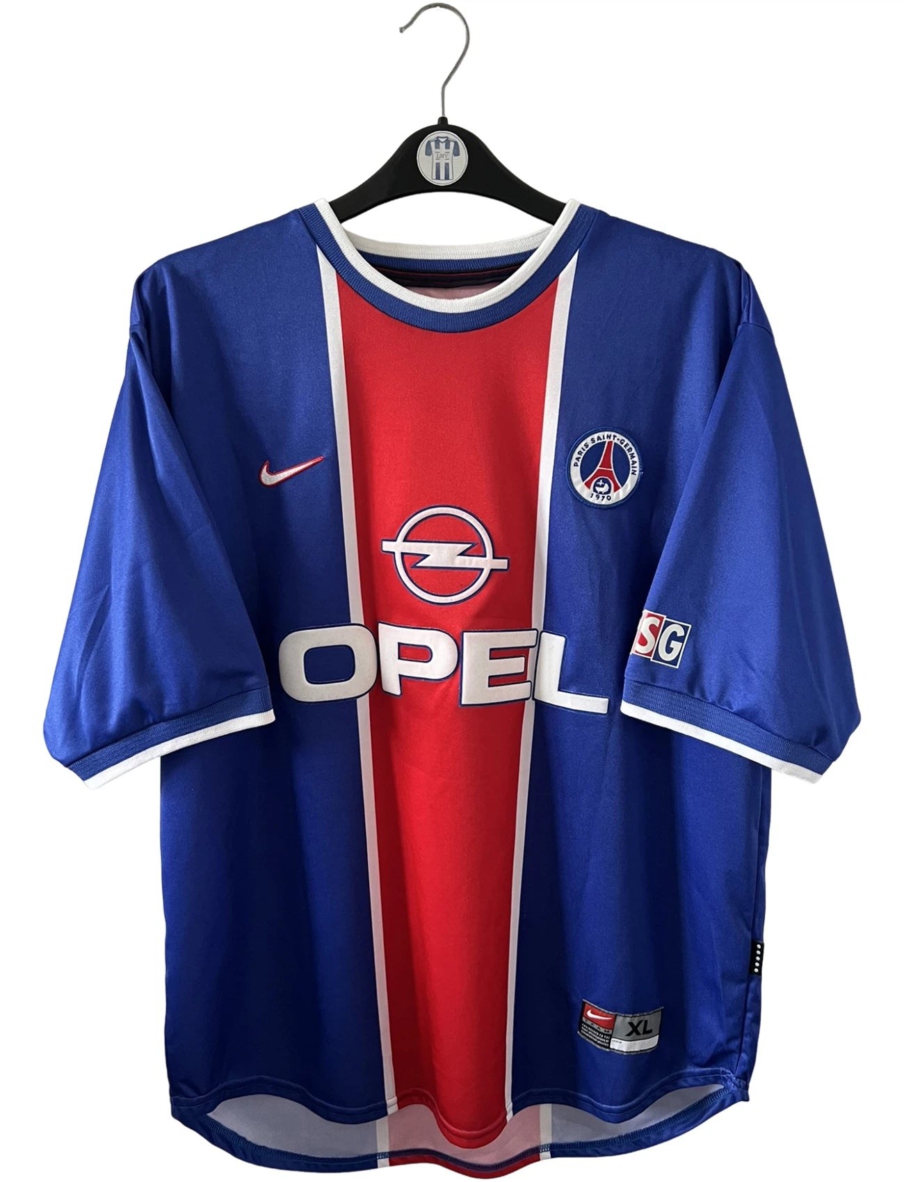 Maillot de foot vintage domicile blanc et rouge du PSG 1999/2000. On peut retrouver l'équipementier Nike et le sponsor Opel. Il s'agit d'un maillot authentique d'époque.
