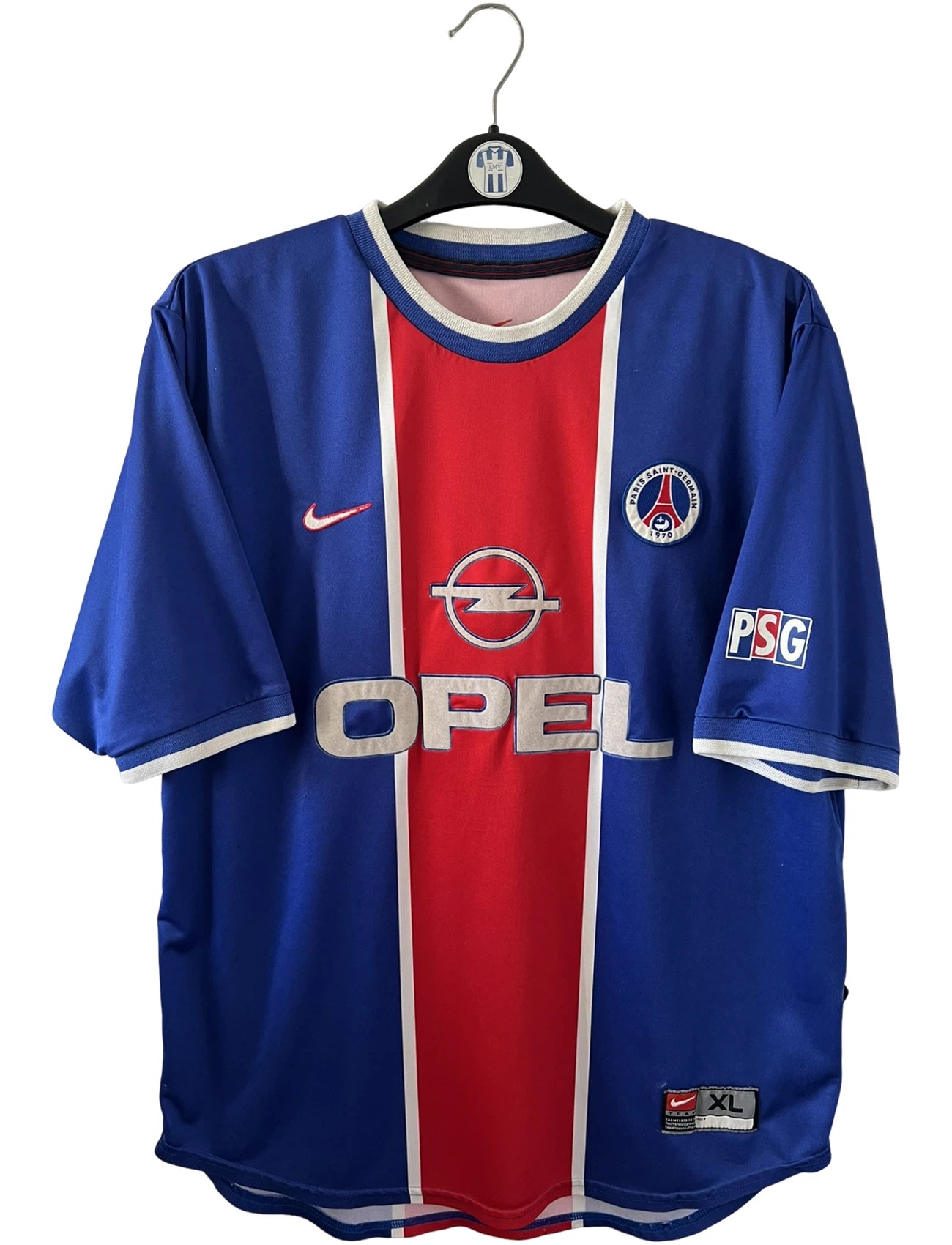 Maillot de foot vintage domicile bleu et rouge du PSG 1999/2000. On peut retrouver l'équipementier Nike et le sponsor Opel. Il s'agit d'un maillot authentique d'époque.