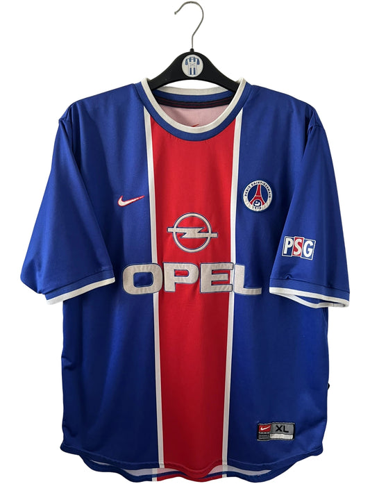 Maillot de foot vintage domicile bleu et rouge du PSG 1999/2000. On peut retrouver l'équipementier Nike et le sponsor Opel. Il s'agit d'un maillot authentique d'époque.