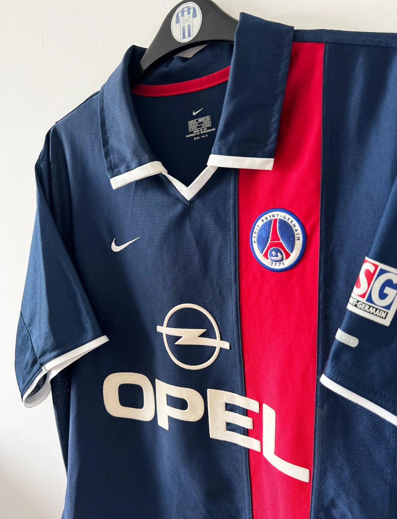 Maillot de foot vintage domicile bleu et rouge du PSG 2001/2002. On peut retrouver l'équipementier Nike et le sponsor Opel. Il s'agit d'un maillot authentique d'époque.