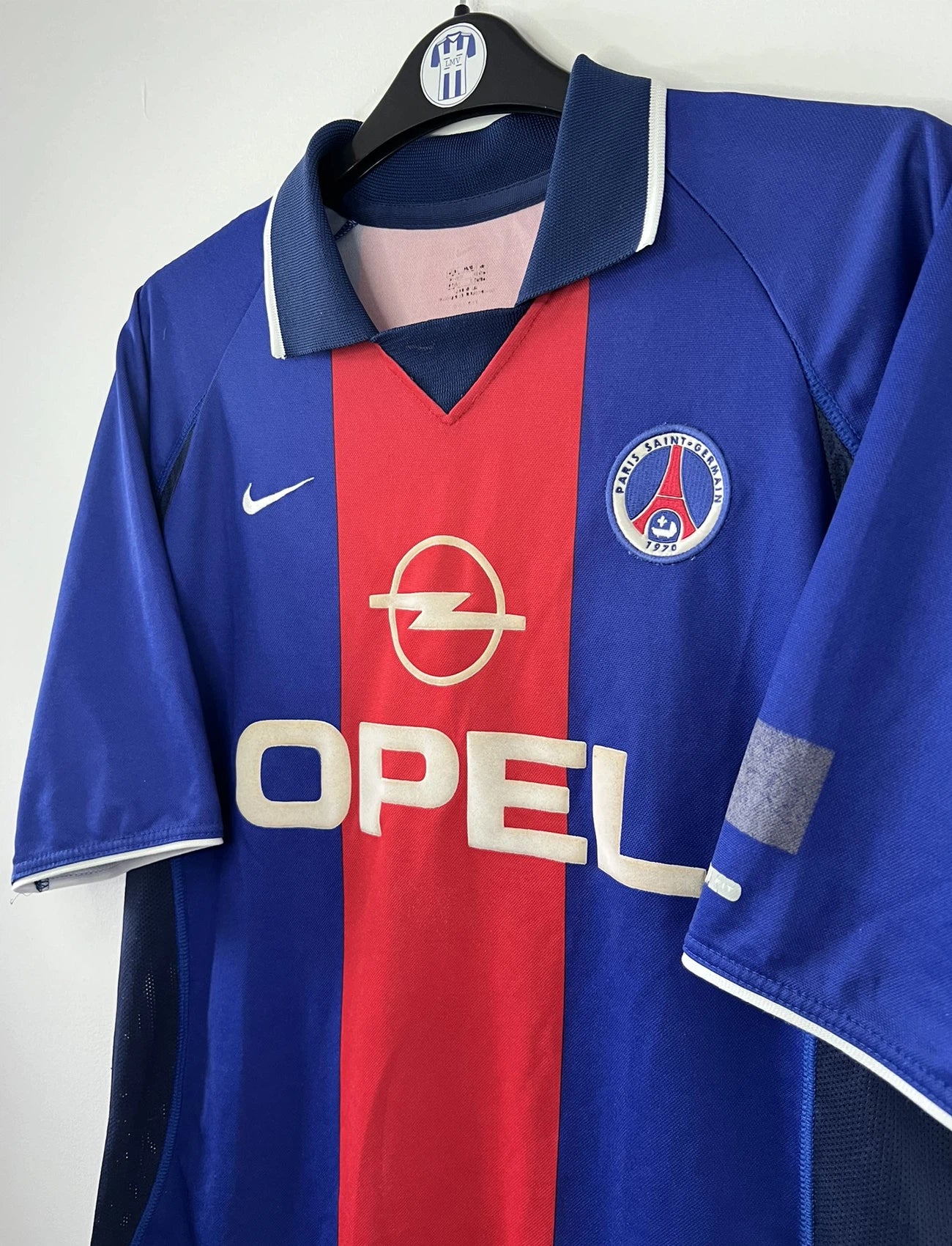 Maillot de foot vintage domicile du PSG de la saison 2000/2001. Le maillot est de couleur bleu et rouge. On peut retrouver l'équipementier nike et le sponsor OPEL