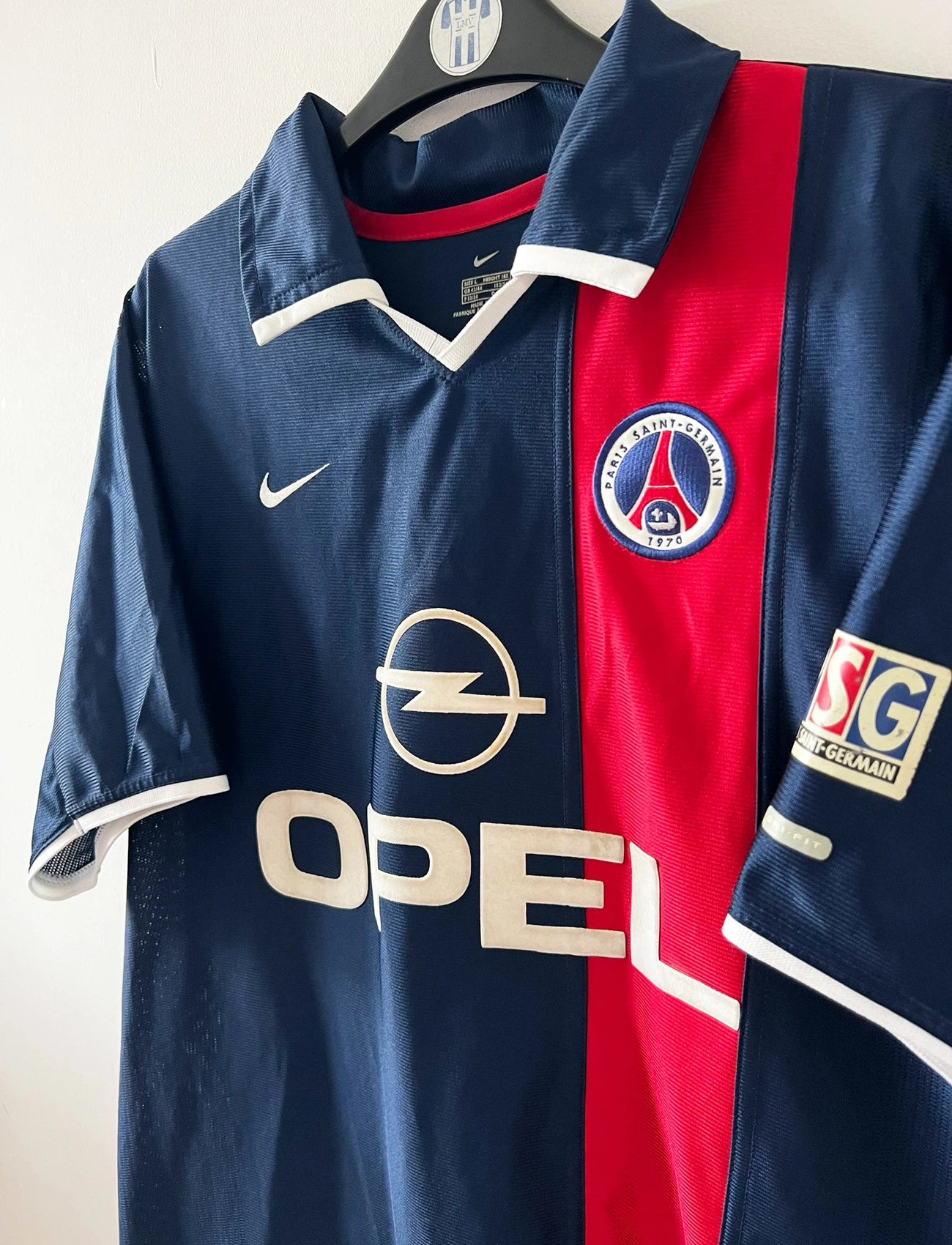 Maillot de foot vintage domicile bleu du PSG 2001/2002. On peut retrouver l'équipementier Nike et le sponsor Opel. Le maillot est floqué du numéro 11 Alex. Il s'agit d'un maillot authentique d'époque.