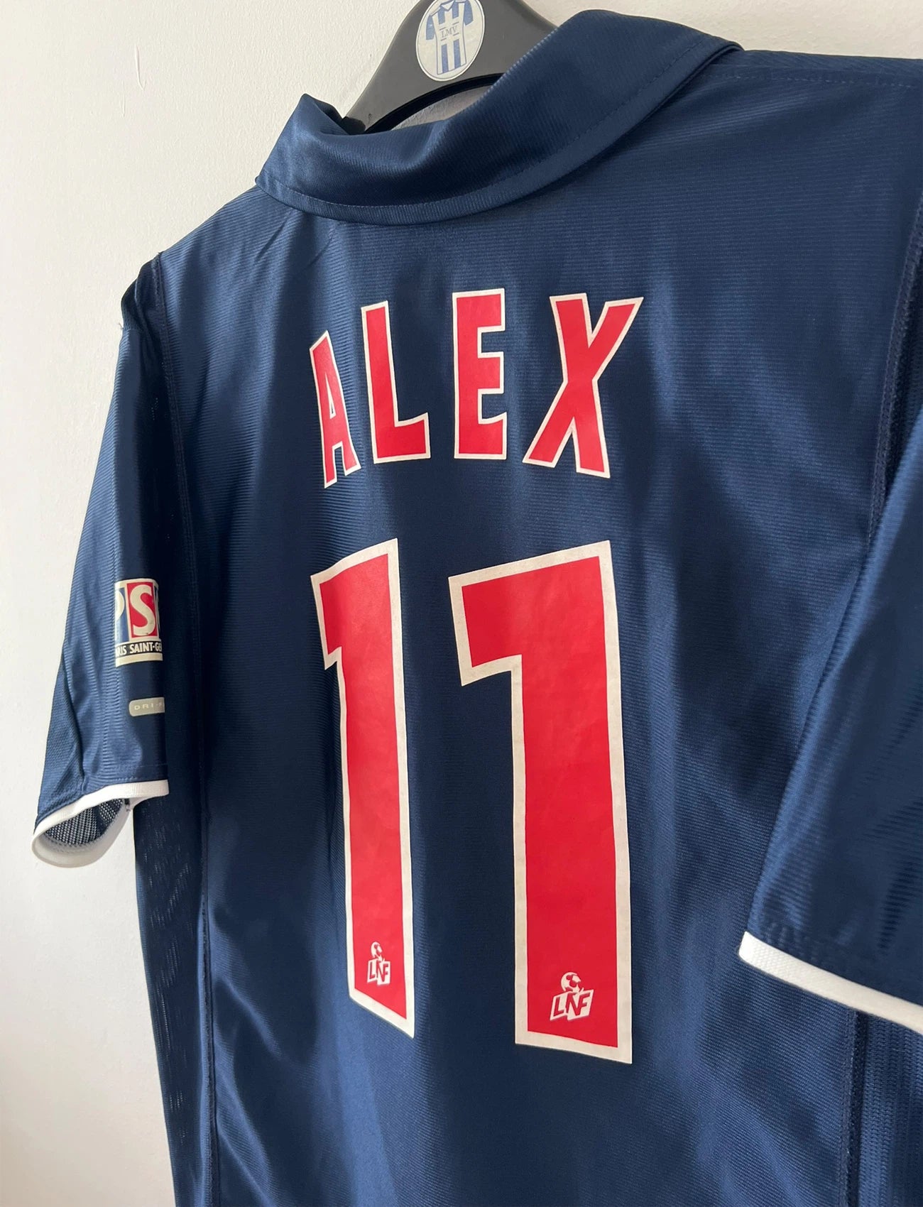 Maillot de foot vintage domicile bleu du PSG 2001/2002. On peut retrouver l'équipementier Nike et le sponsor Opel. Le maillot est floqué du numéro 11 Alex. Il s'agit d'un maillot authentique d'époque.