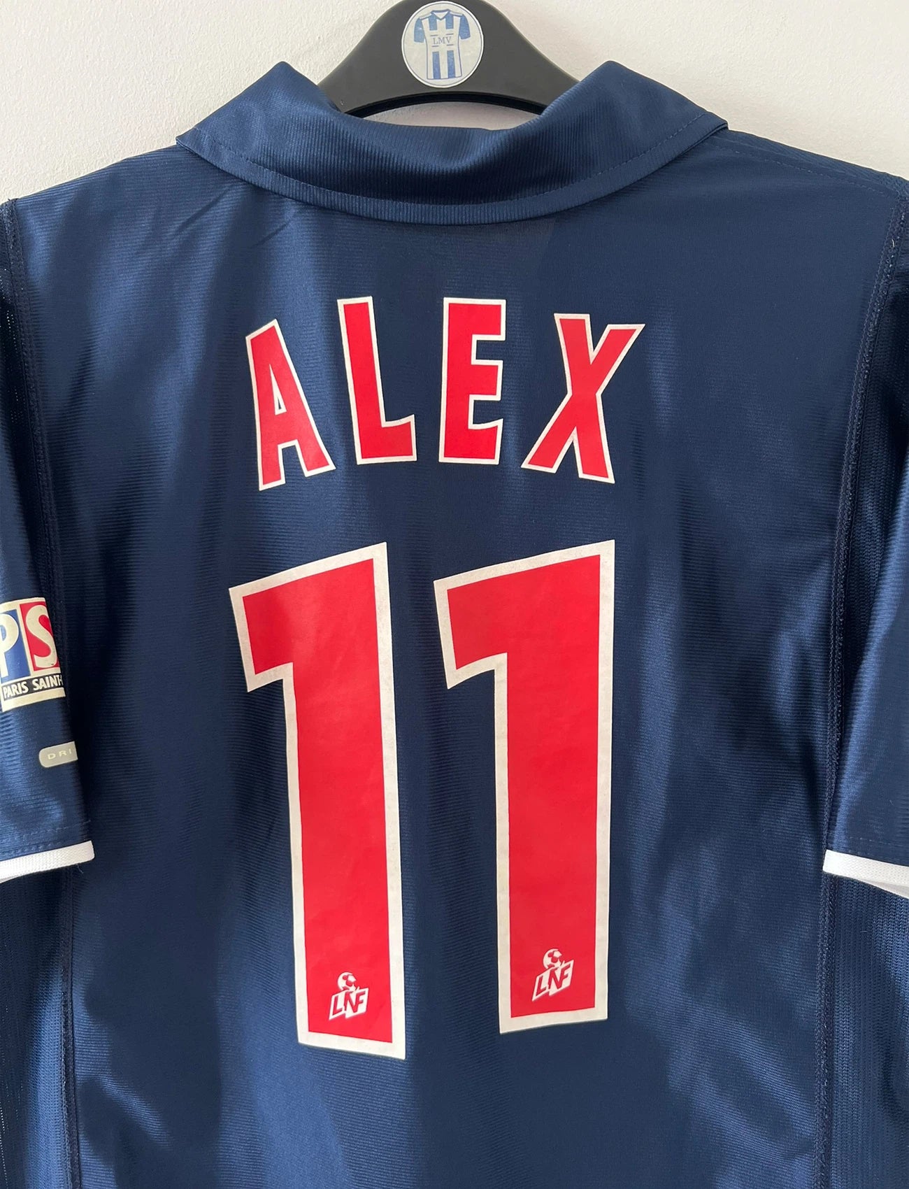 Maillot de foot vintage domicile bleu du PSG 2001/2002. On peut retrouver l'équipementier Nike et le sponsor Opel. Le maillot est floqué du numéro 11 Alex. Il s'agit d'un maillot authentique d'époque.