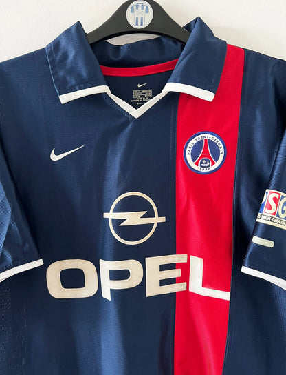 Maillot de foot vintage domicile bleu du PSG 2001/2002. On peut retrouver l'équipementier Nike et le sponsor Opel. Le maillot est floqué du numéro 11 Alex. Il s'agit d'un maillot authentique d'époque.