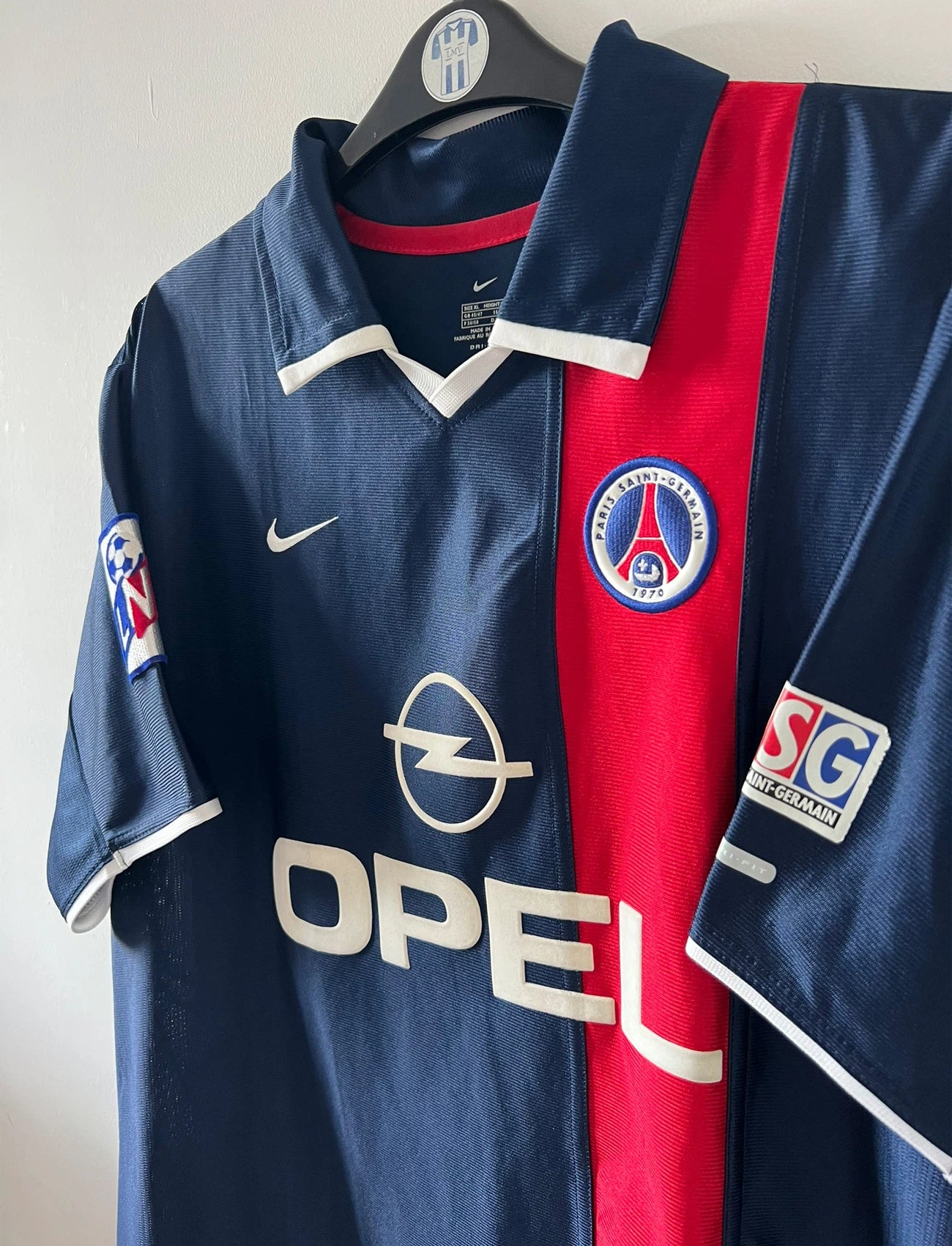 Maillot de foot vintage domicile bleu du PSG 2001/2002. On peut retrouver l'équipementier Nike et le sponsor Opel. Le maillot est floqué du numéro 7 Aloisio. Il s'agit d'un maillot authentique d'époque.
