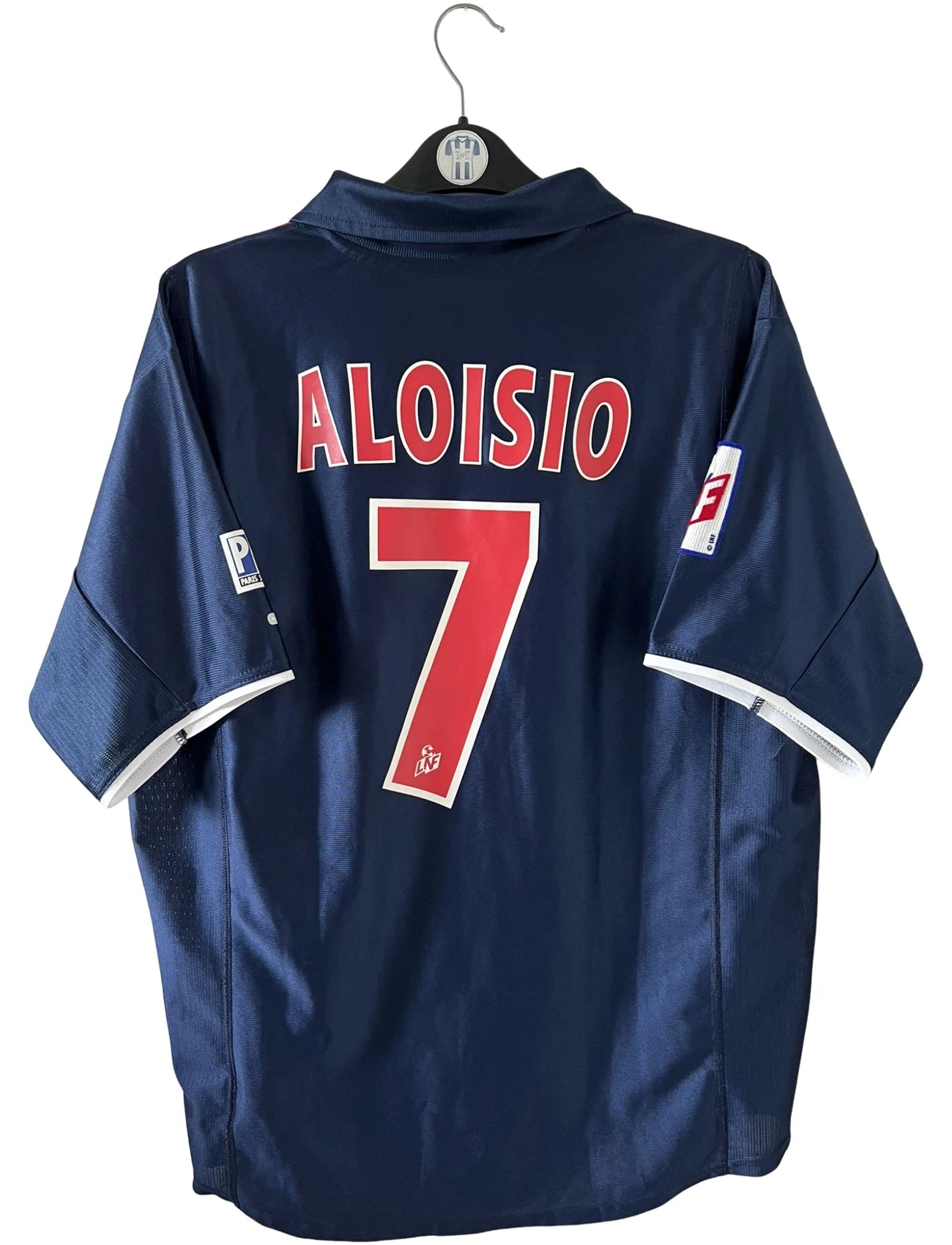 Maillot de foot vintage domicile bleu du PSG 2001/2002. On peut retrouver l'équipementier Nike et le sponsor Opel. Le maillot est floqué du numéro 7 Aloisio. Il s'agit d'un maillot authentique d'époque.