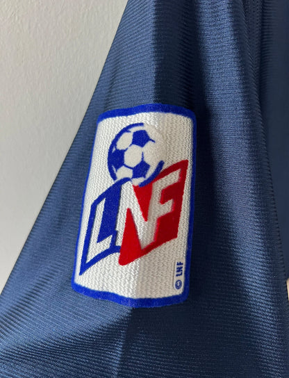 Maillot de foot vintage domicile bleu du PSG 2001/2002. On peut retrouver l'équipementier Nike et le sponsor Opel. Le maillot est floqué du numéro 7 Aloisio. Il s'agit d'un maillot authentique d'époque.