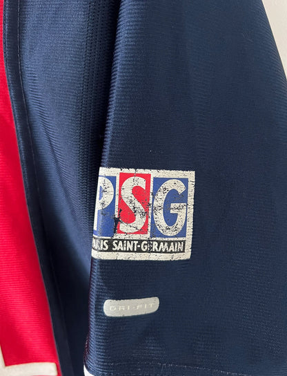 Maillot de foot vintage domicile bleu du PSG de la saison 2001/2002. On peut retrouver l'équipementier Nike et le sponsor Opel. Il s'agit d'un maillot authentique d'époque.