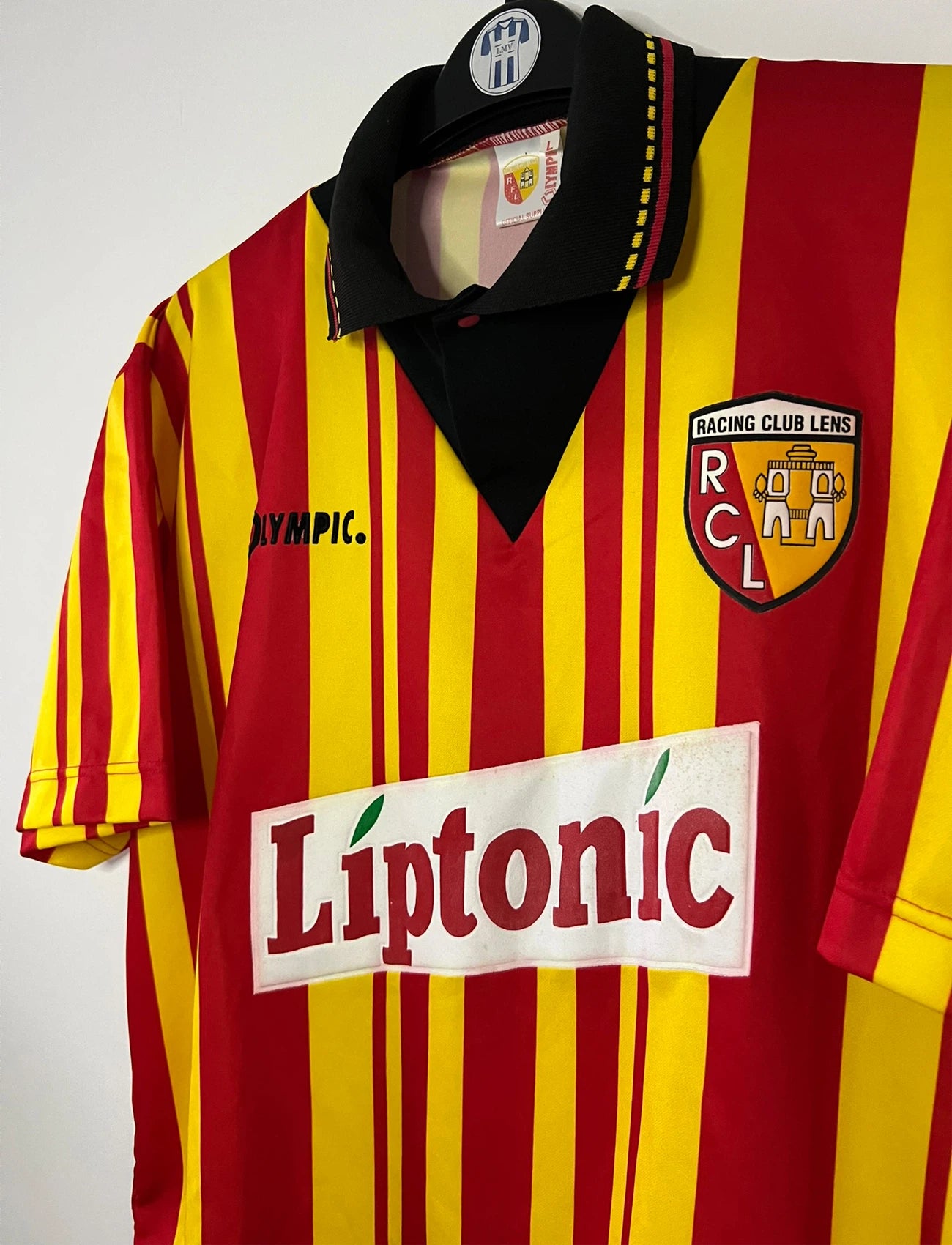 Maillot de foot vintage domicile rouge et jaune du RC Lens de la saison 1994/1995. On peut retrouver l'équipementier Olympic et le sponsor Liptonic. Il s'agit d'un maillot authentique d'époque.