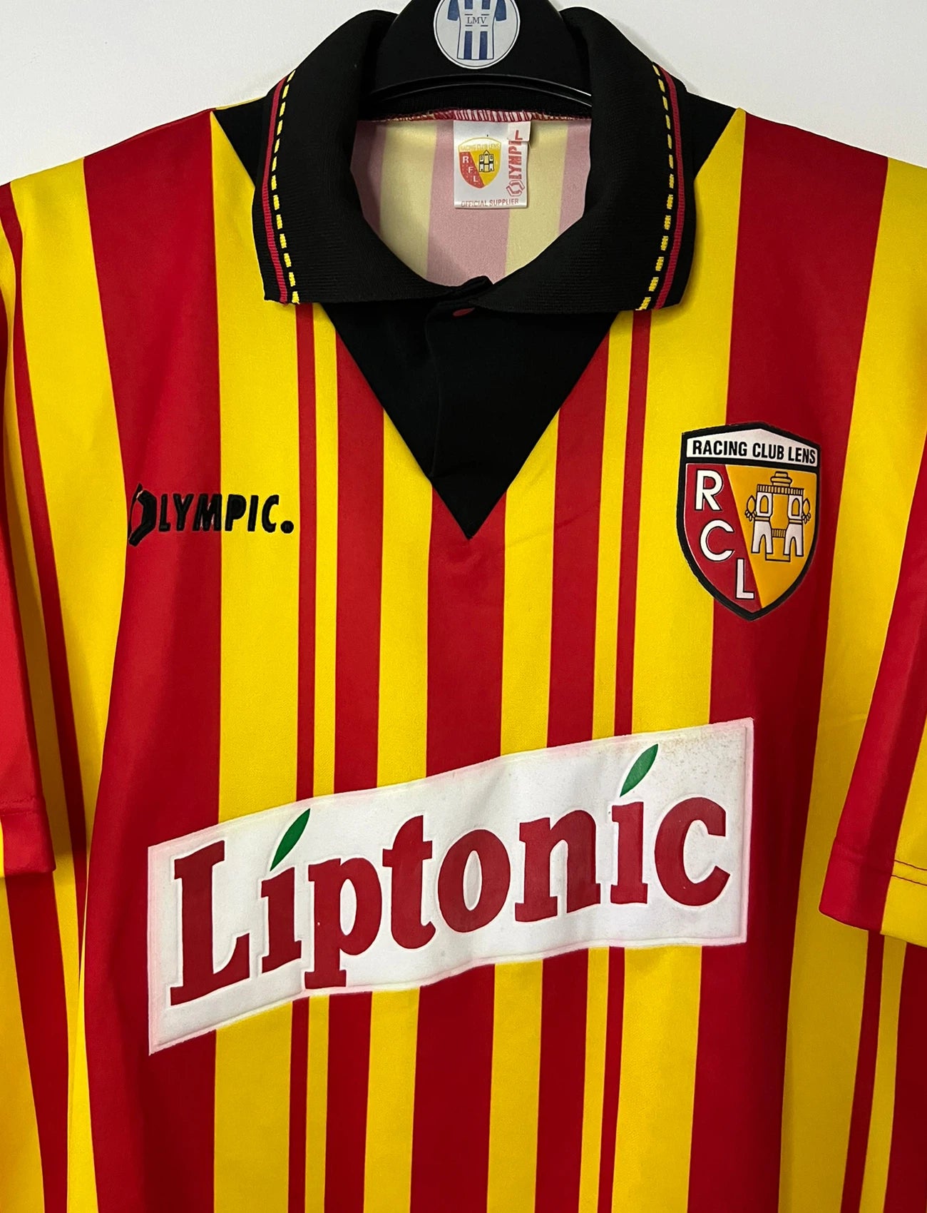 Maillot de foot vintage domicile rouge et jaune du RC Lens de la saison 1994/1995. On peut retrouver l'équipementier Olympic et le sponsor Liptonic. Il s'agit d'un maillot authentique d'époque.