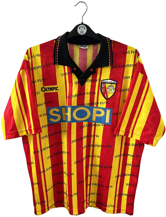 Maillot de foot vintage domicile jaune et rouge du RC Lens 1995/1996. Il s'agit d'une version Lens Européen 95/96. On peut retrouver l'équipementier Olympic et le sponsor Shopi. Il s'agit d'un maillot authentique d'époque.