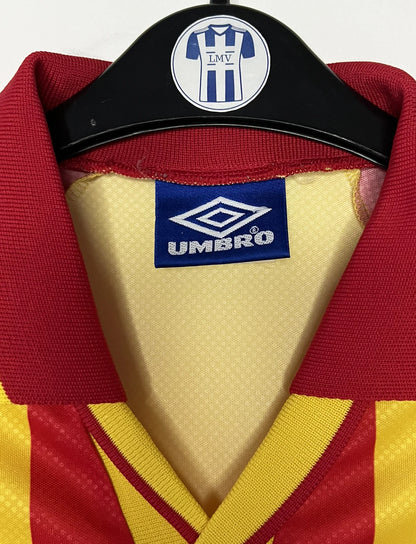 Maillot de foot vintage domicile jaune et rouge du RC Lens de la saison 1998/1999. On peut retrouver l'équipementier Umbro et le sponsor OLA. Il s'agit d'un maillot authentique d'époque.