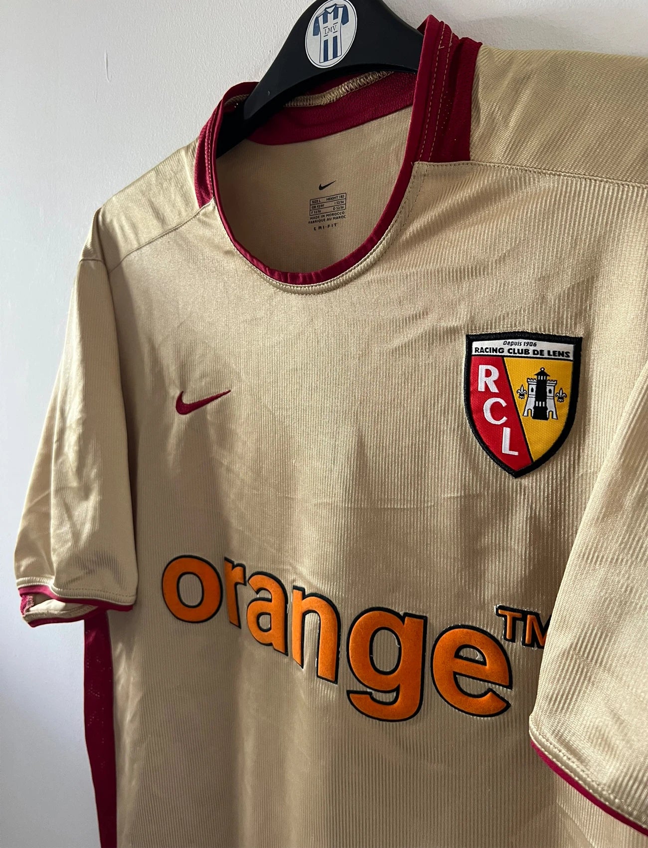 Maillot de foot vintage domicile doré du RC Lens de la saison 2002/2003. On peut retrouver l'équipementier Nike et le sponsor Orange. Il s'agit d'un maillot authentique d'époque.