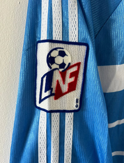 Maillot de foot vintage domicile bleu de strasbourg de la saison 1999/2000. On peut retrouver l'équipementier Adidas et le sponsor Canal+. Il s'agit d'un maillot authentique d'époque, issu du stock pro du club