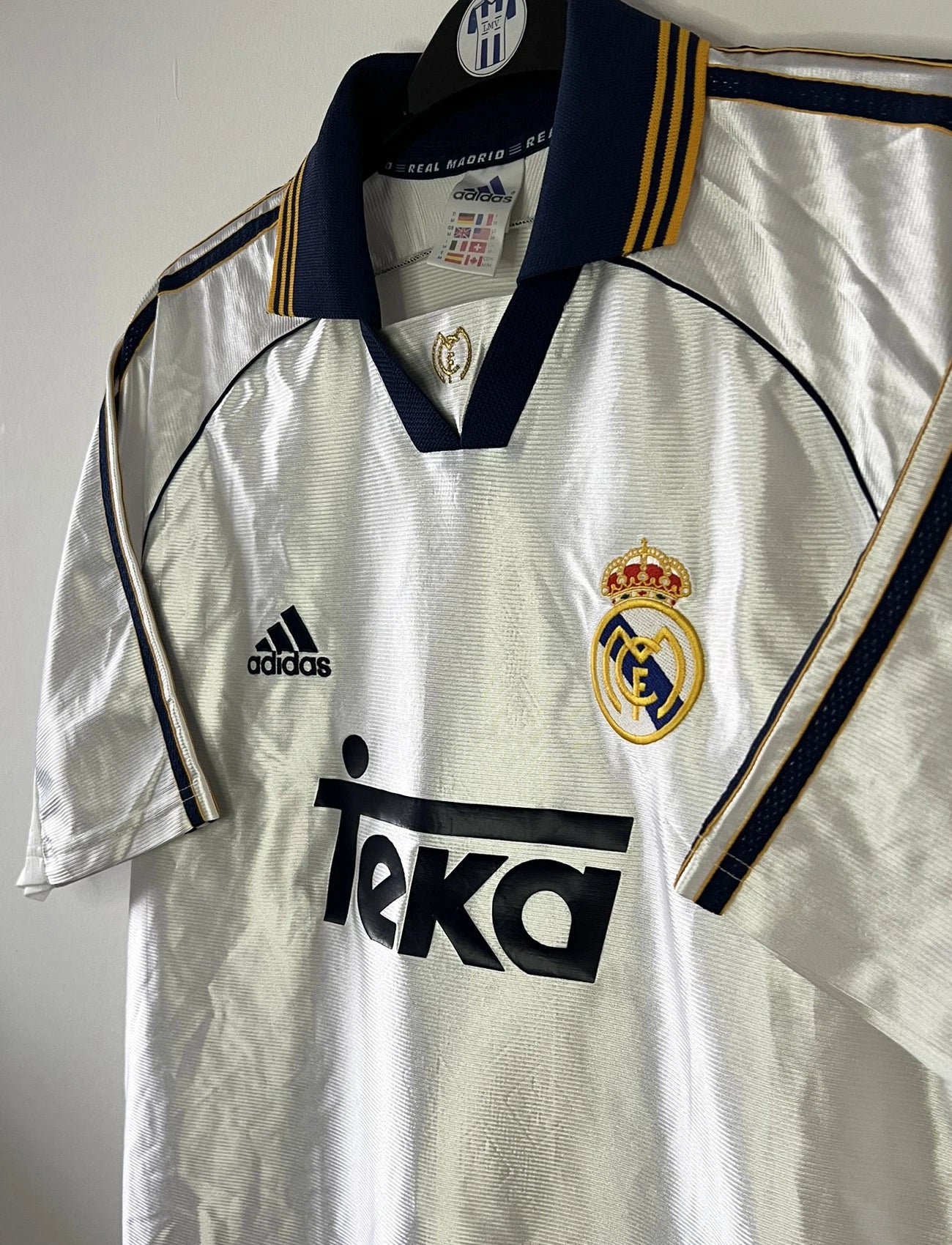 Maillot de foot vintage domicile blanc du Real Madrid de la saison 1998/1999. On peut retrouver l'équipementier Adidas et le sponsor Teka. Il s'agit d'un maillot authentique d'époque.